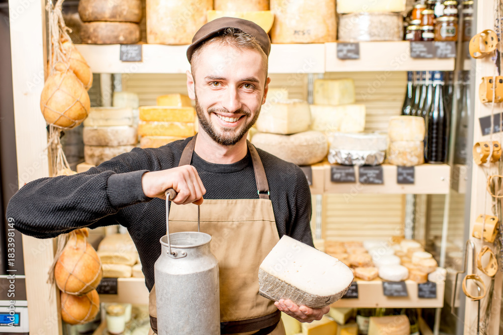 一个拿着大奶桶的奶酪小贩站在奶酪店里的画像