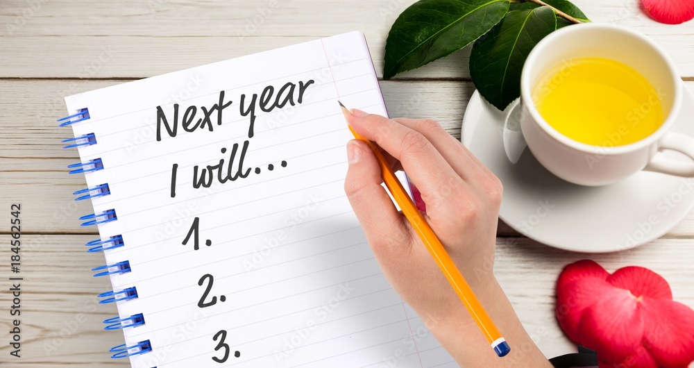 用铅笔在记事本上写新年决心的手的俯视图