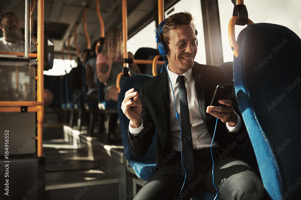 年轻的商人坐在公交车上听音乐