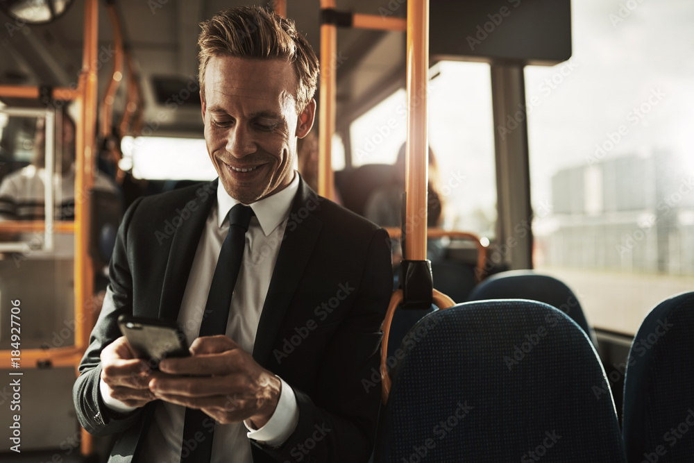 微笑的年轻商人站在公交车上发送短信