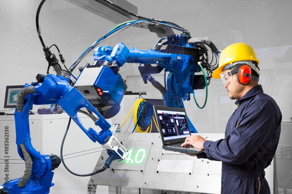 。工程师使用labtop计算机控制激光机器人在金属板上切割，工业4.0概念