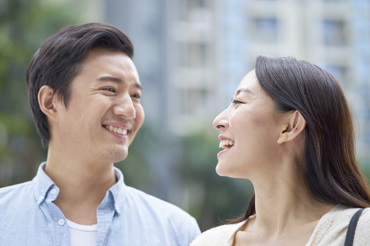 portrait of young Chinese couple standing & smiling outdoor in garden