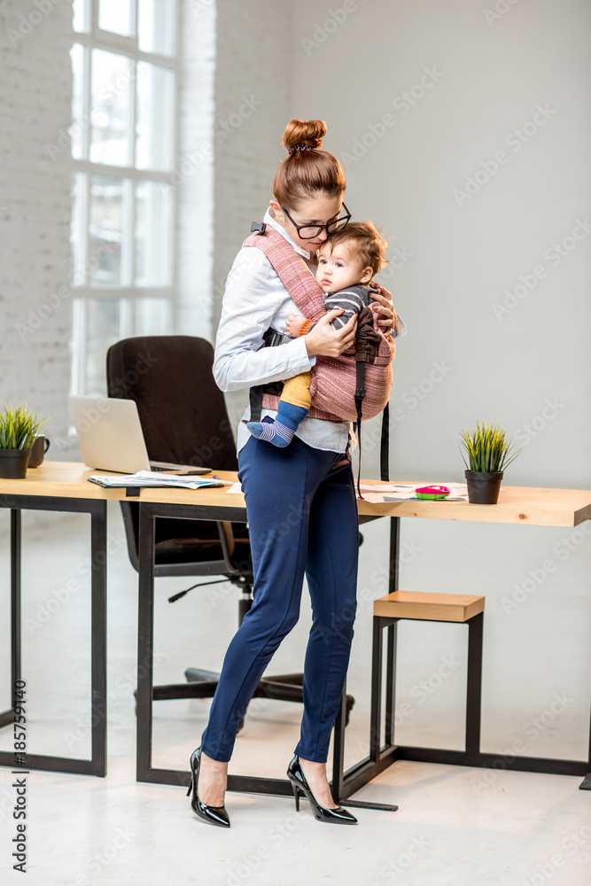 一位优雅的女商人在白色办公室抱着她的小儿子的全身照