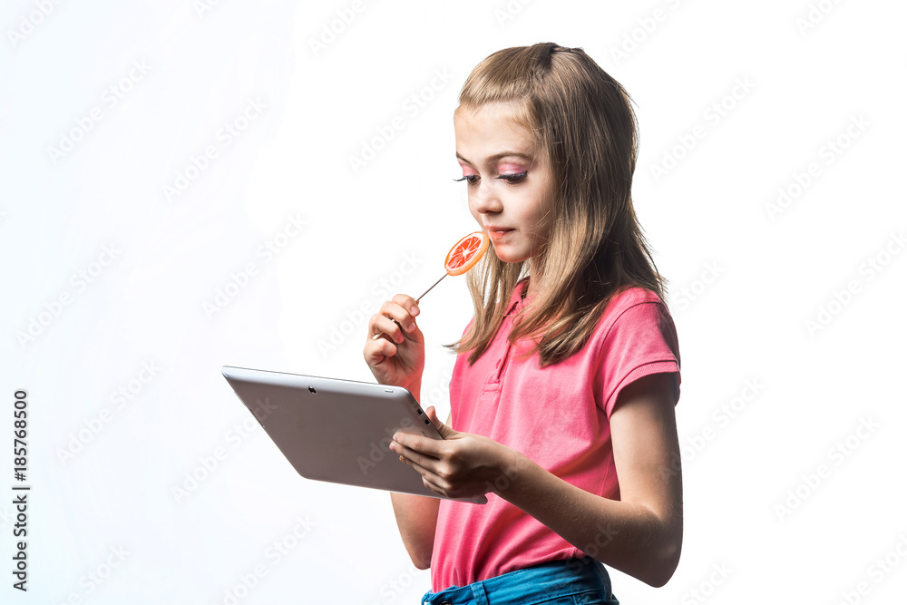 小女孩拿着平板电脑，白色背景上有糖果。孩子的情绪。