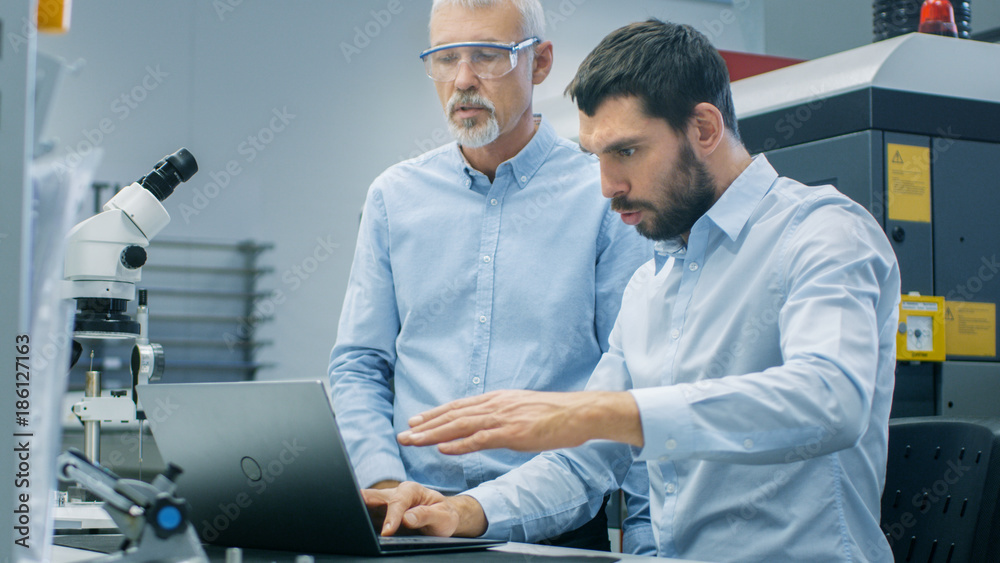 两位工业科学家/工程师/技术人员在笔记本电脑上工作时进行讨论