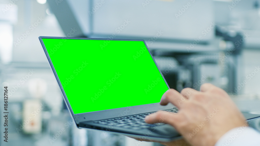 工程师手持笔记本电脑的特写，带有绿屏Chroma键模板，非常适合实物模型。In t