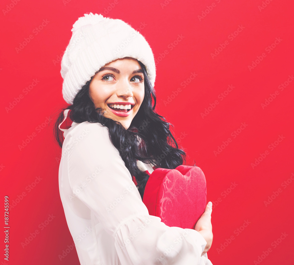 快乐的年轻女人在坚实的背景上拿着一个大大的爱心礼盒