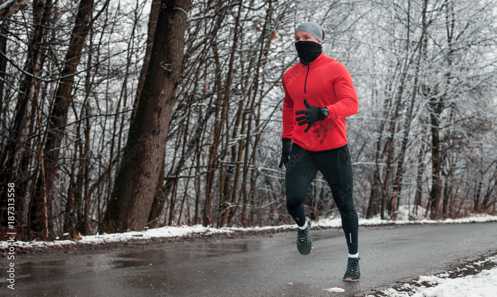 冬季跑步运动，雪地森林中的公路跑步者