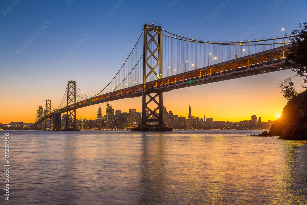 美国加利福尼亚州日落时旧金山与奥克兰湾大桥的天际线