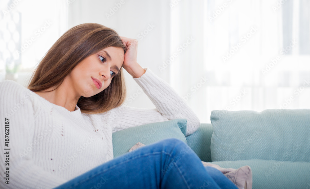 悲伤的女人坐在家里的沙发上沉思，思考概念