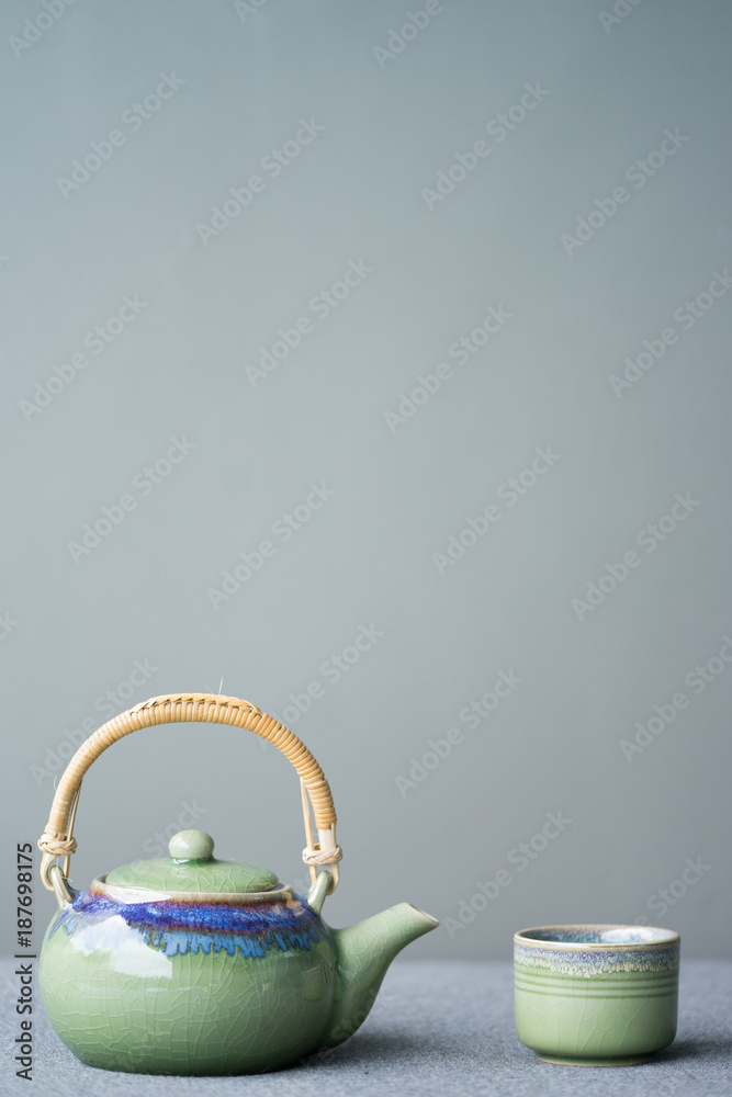桌子上传统的东方绿色茶壶和茶杯的图像。
