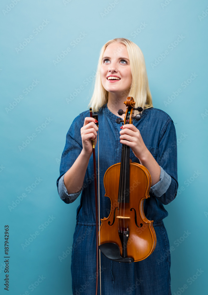 年轻女子在坚实的背景下拉小提琴