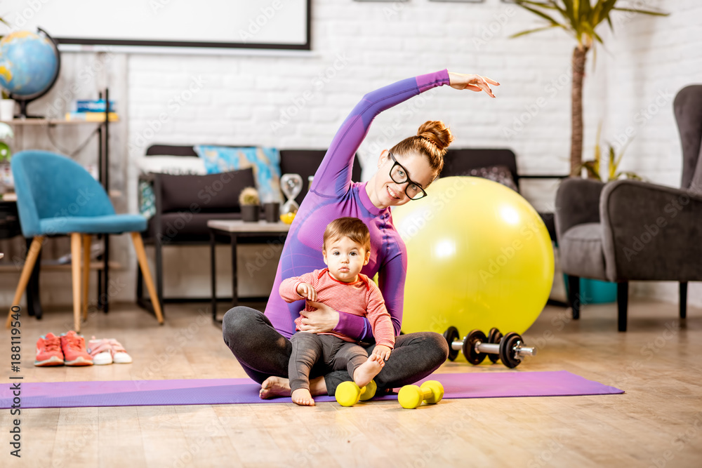 穿着运动服的年轻母亲在家里的垫子上和她的小儿子一起锻炼