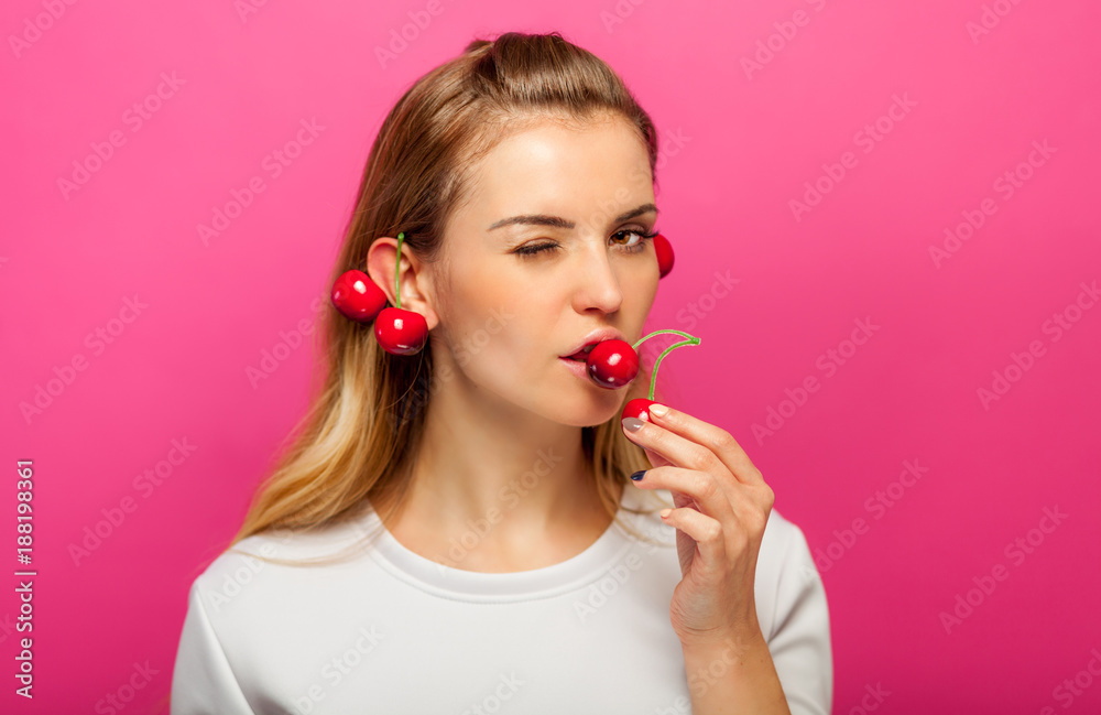 粉红色背景的女人在吃樱桃果