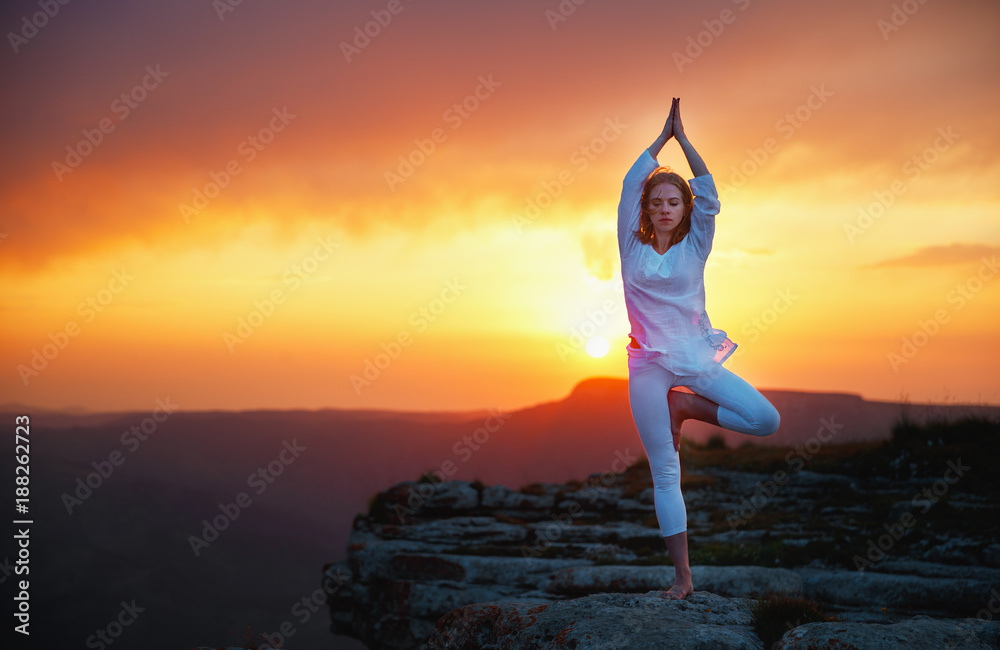 女人在日落的山上练习瑜伽和冥想