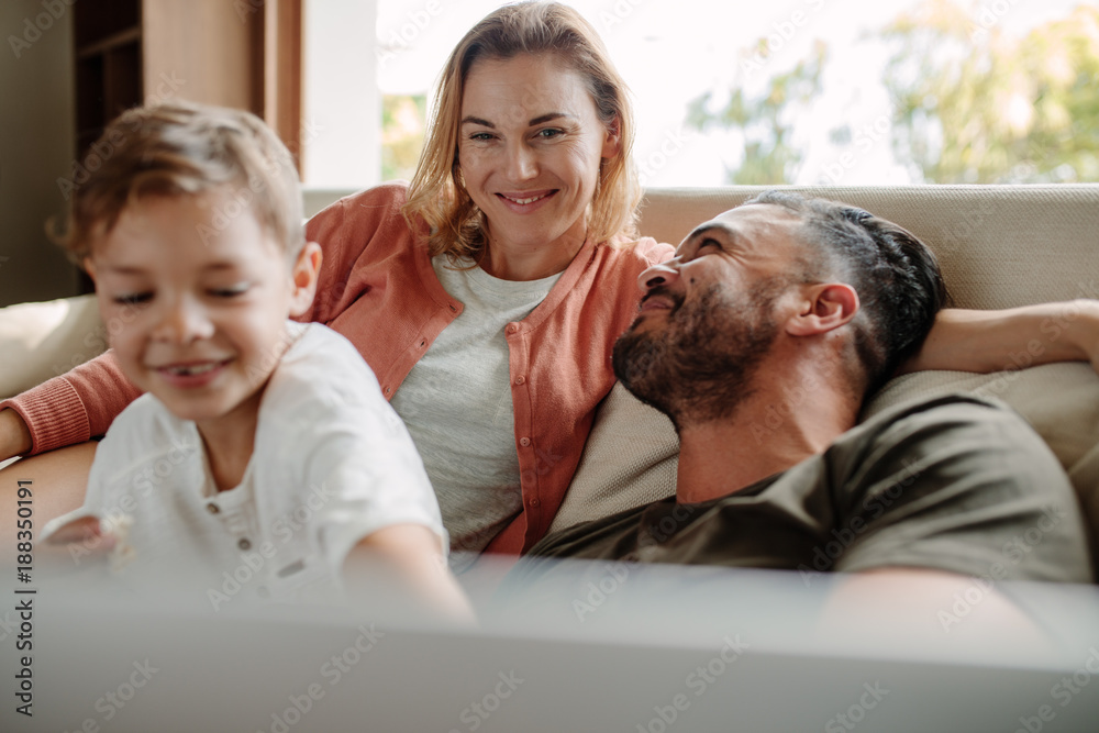 Happy young family relaxing on couch at home
