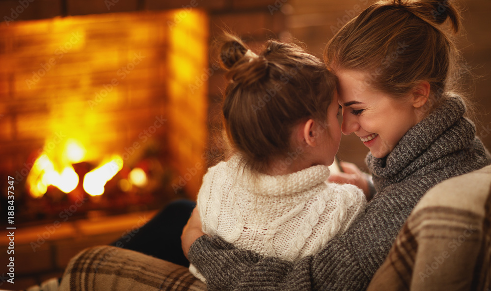 冬日夜晚，家里的母亲和孩子在壁炉旁拥抱大笑