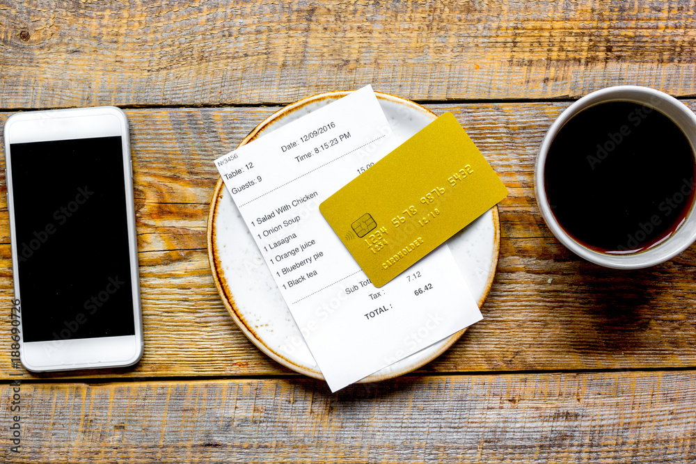 用信用卡和电话在木桌上支付餐厅账单