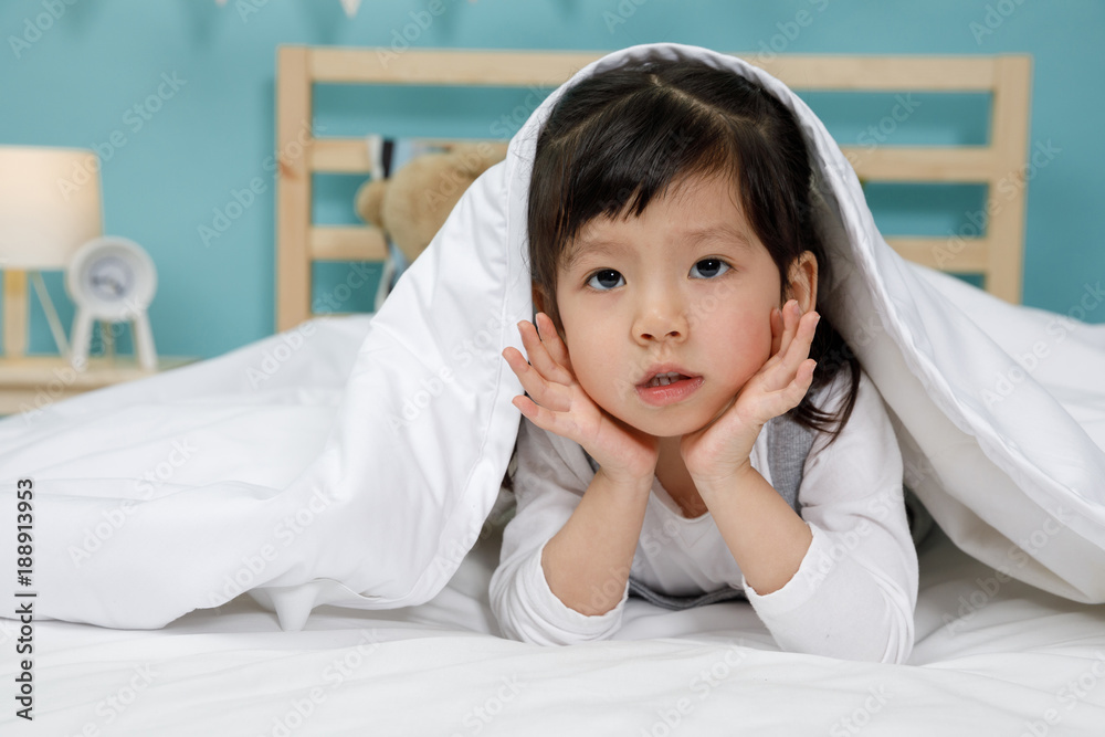 Child girl in the blanket on the wooden bed in her bedroom, Happy asian child little girl sleeping o