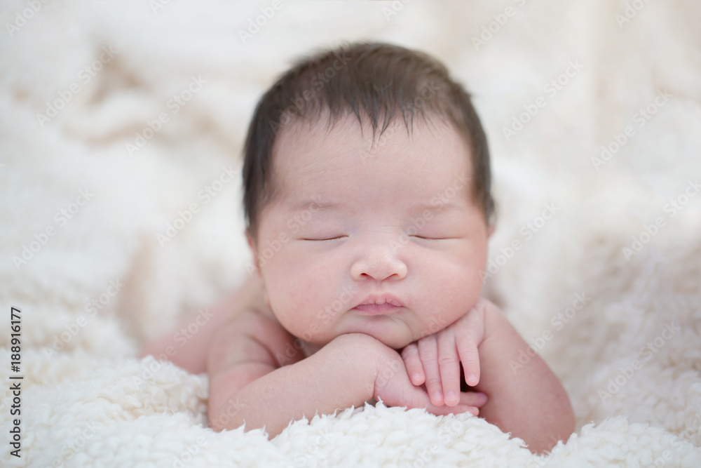可爱的亚洲新生儿睡在毛茸茸的毯子上