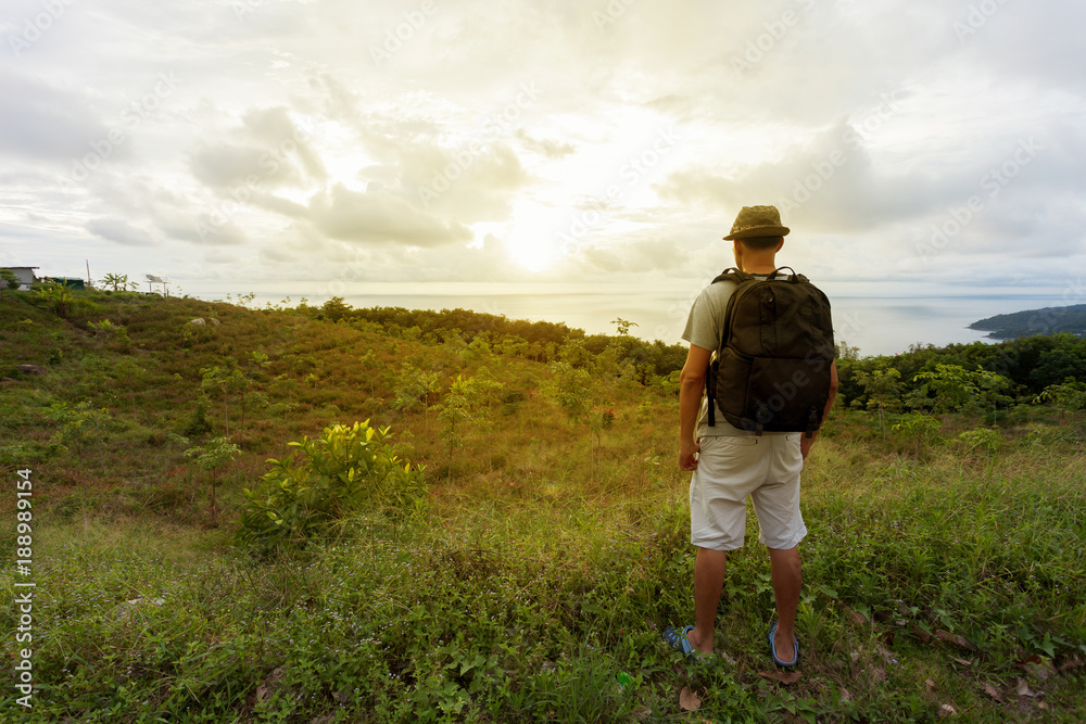 泰国普吉岛，年轻的旅行者站在日落的风景下放松。