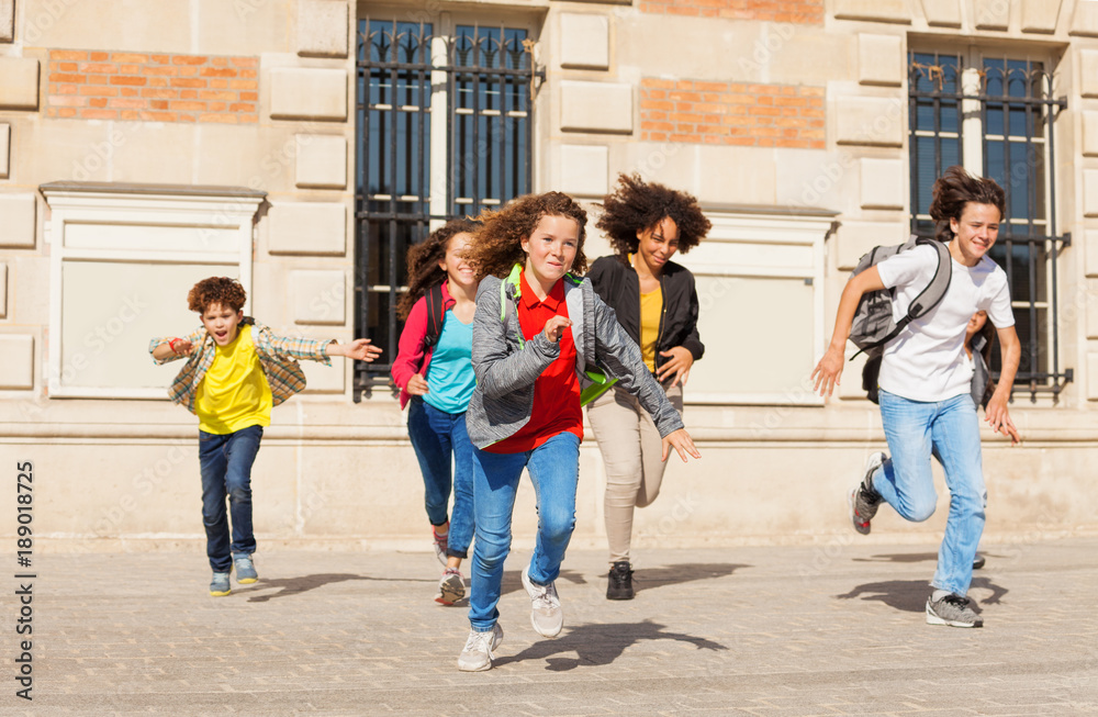 Cute pupils running  from school building