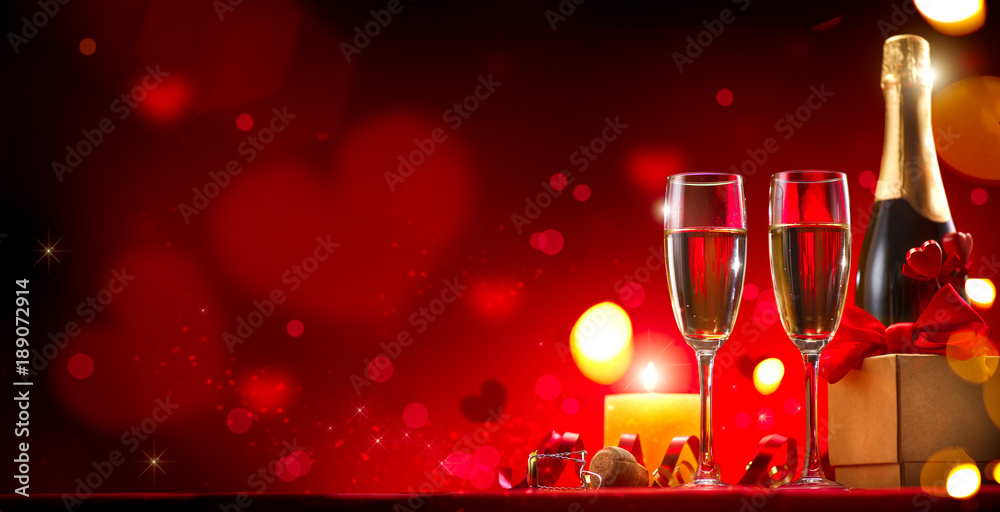 情人节浪漫晚餐。香槟、蜡烛和节日红背景礼盒