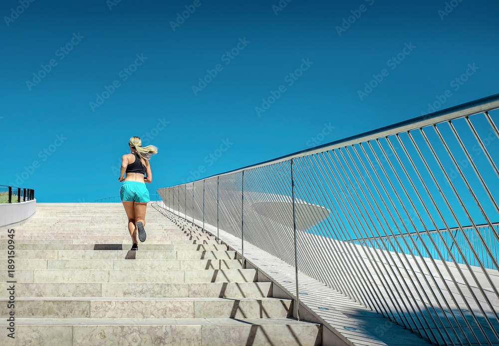 金发女子在现代建筑附近跑步训练