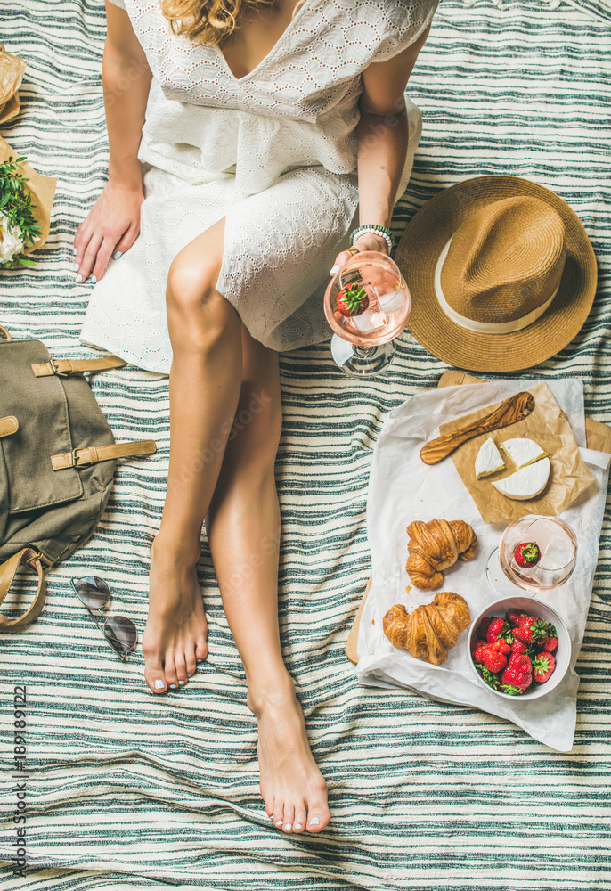 法式浪漫野餐场景。穿着连衣裙的女人拿着一杯葡萄酒、草莓、羊角面包，b