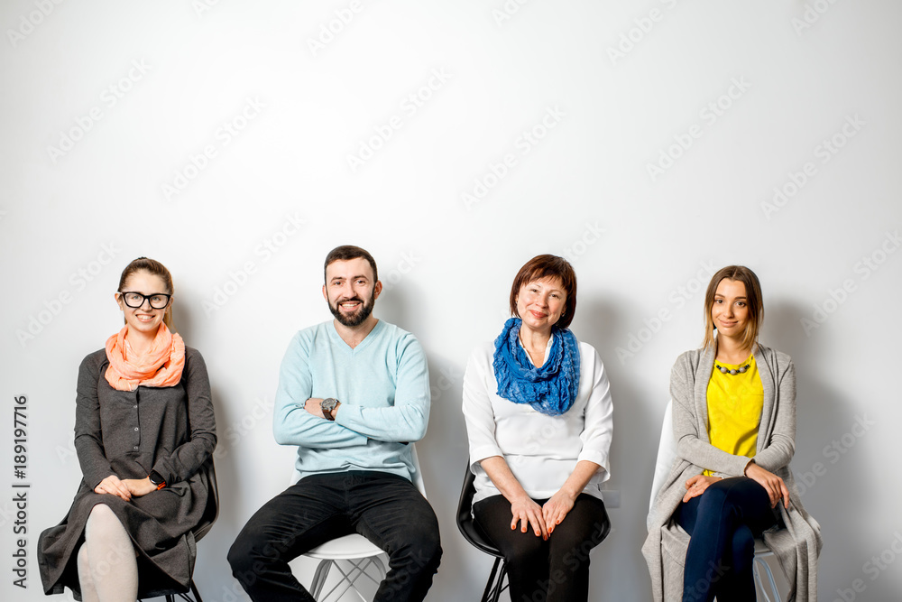 一个穿着五颜六色衣服的人坐在室内白墙上的画像