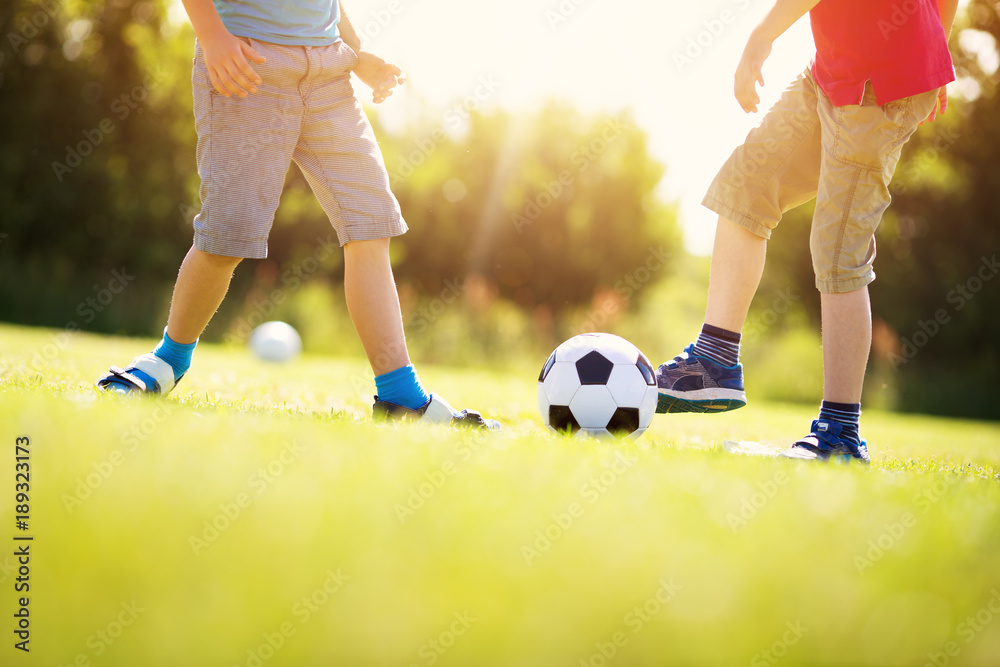 男孩在球场上用大门踢足球。夏天活跃的孩子用球