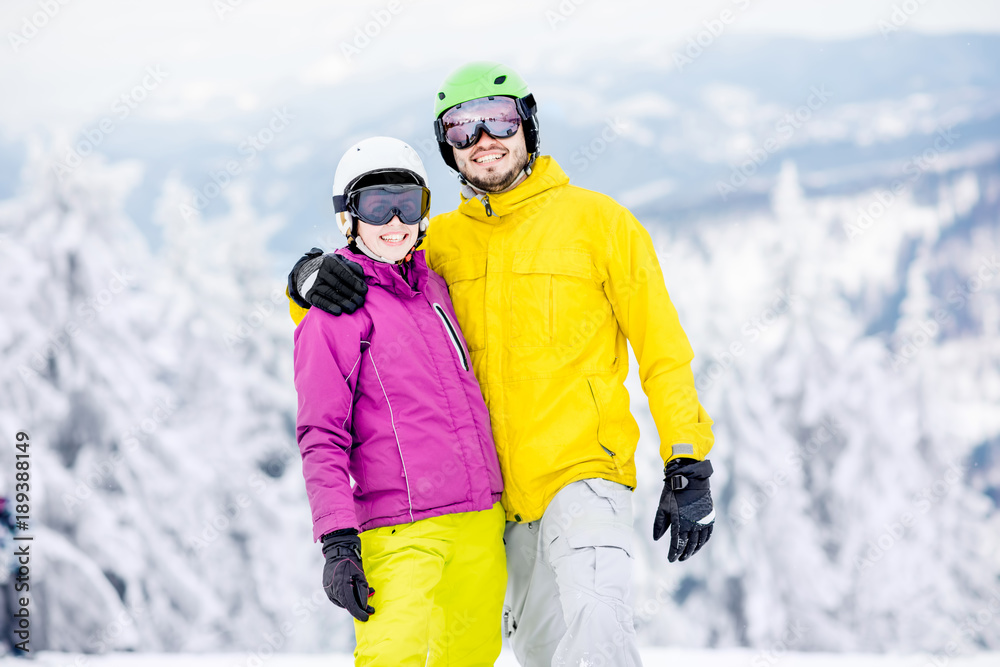 一对年轻快乐的滑雪运动员穿着五颜六色的运动服站在一起的肖像