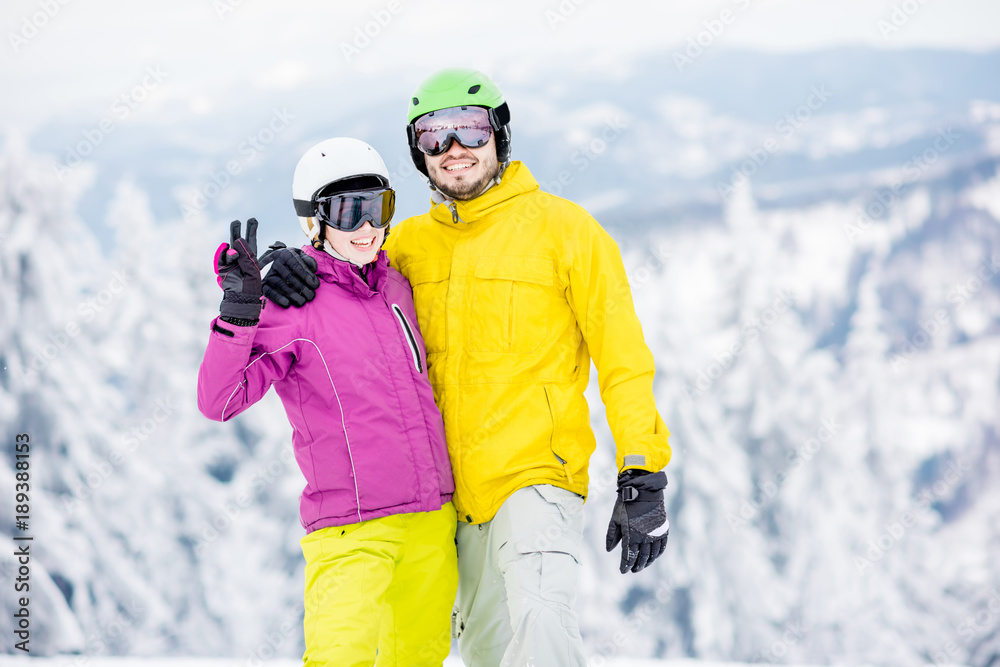 一对年轻快乐的单板滑雪运动员穿着五颜六色的运动服站在一起的肖像