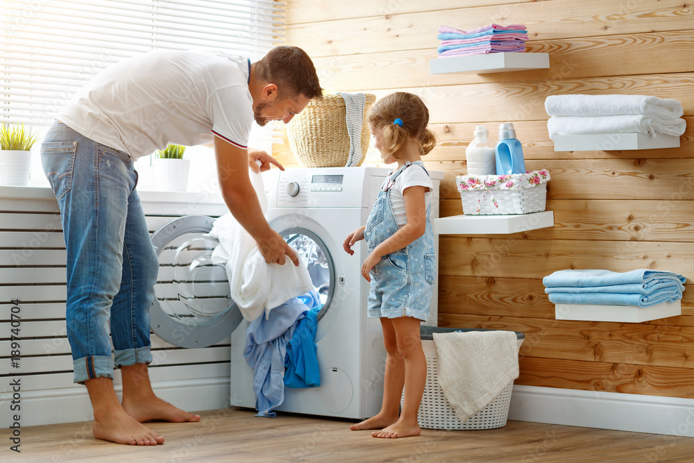 Happy family man father householder and child   in laundry with washing machine