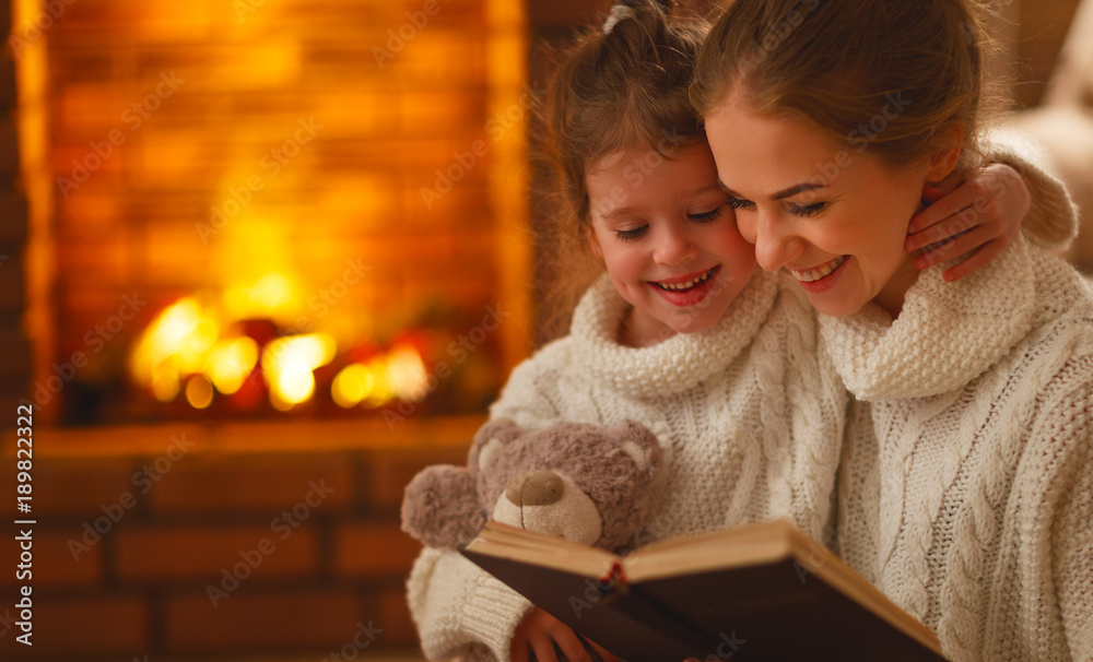 幸福的家庭母亲和孩子的女儿在冬天的晚上读书