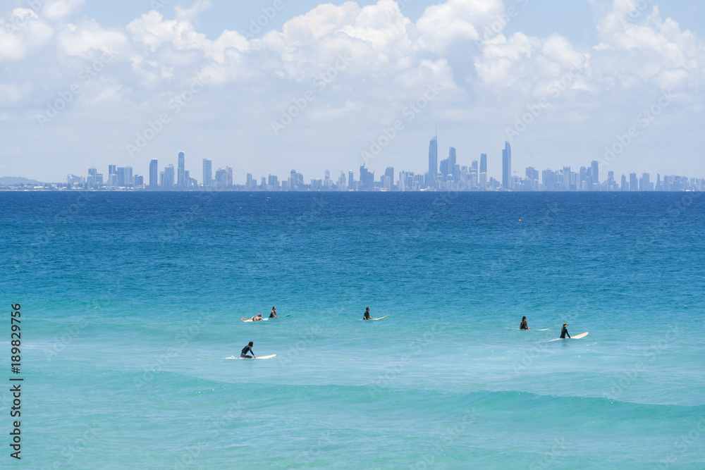 冲浪者坐在冲浪者天堂天际线前的冲浪板上，澳大利亚昆士兰黄金海岸