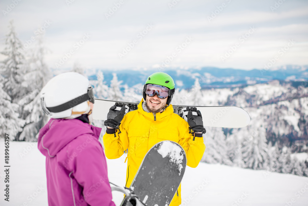 一对穿着冬季运动服的年轻夫妇在寒假里与滑雪板交谈