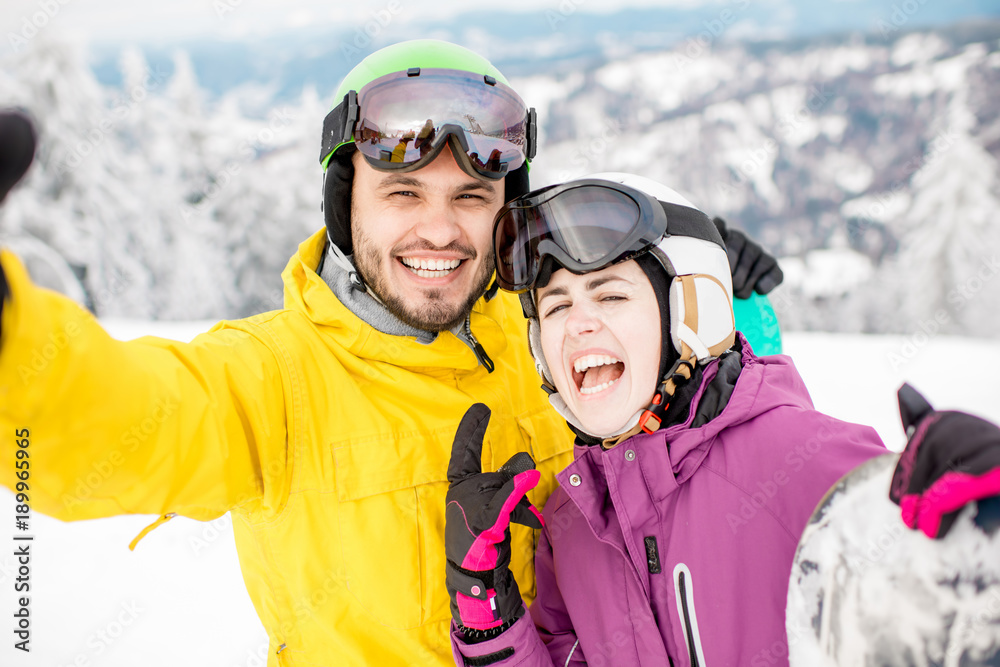 一对年轻夫妇在冬季真空吸尘器中穿着冬季运动服站在一起自拍