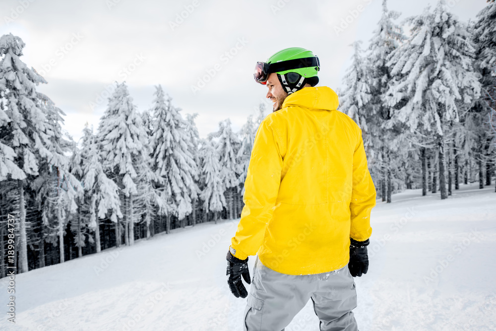 穿着五颜六色运动服的男子在有美丽树木的雪山上滑雪