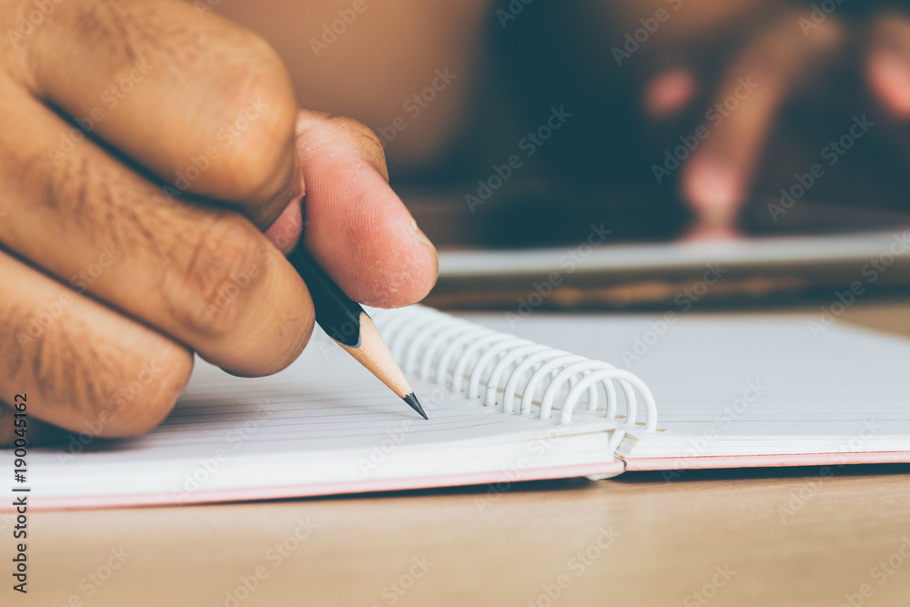 一名男子正在用铅笔在一张纸上写字