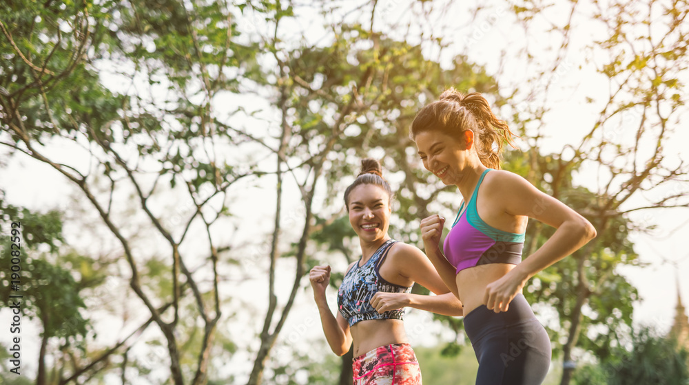 两位运动型女性户外跑步。行动和健康的生活方式理念。公园慢跑