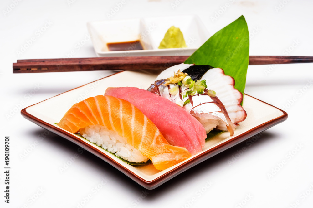 白盘子上的寿司三文鱼、金枪鱼、寿司虾和芥末。选择性关注