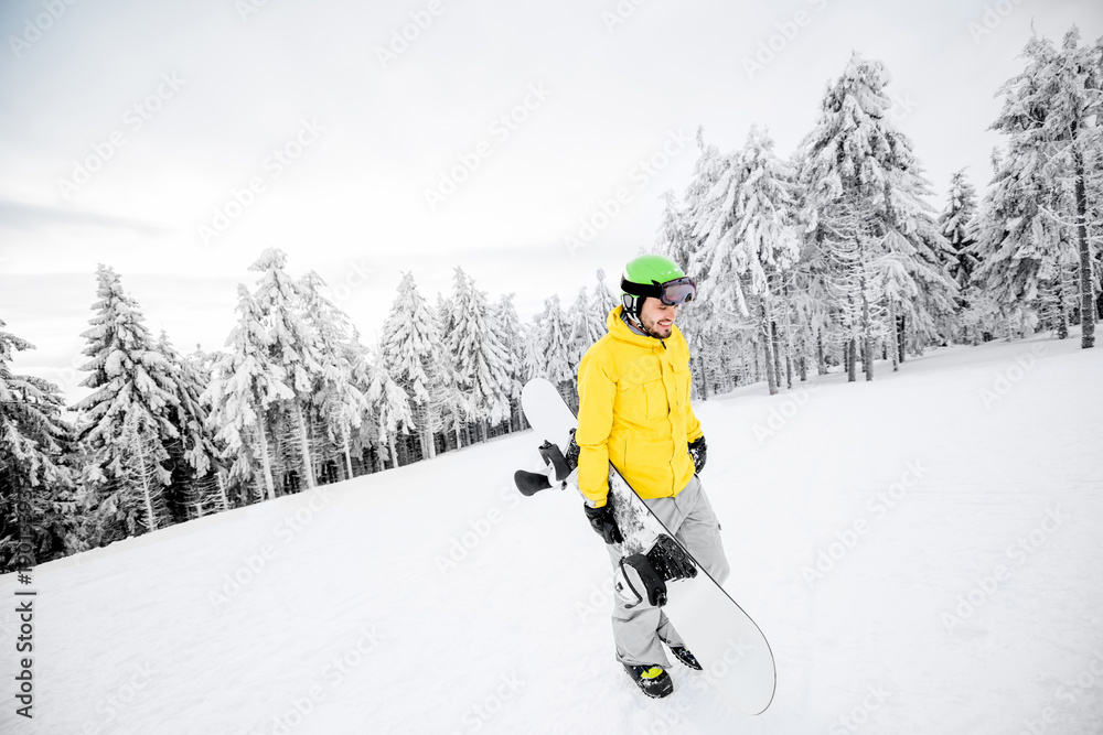 身穿黄色冬装的男子在雪山上滑雪板行走