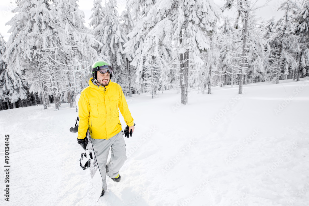 身穿黄色冬装的男子在雪山上滑雪板行走