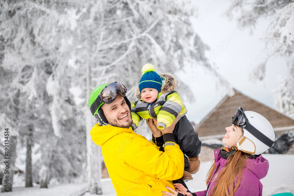 快乐的一家人和站在冬季衣服里的男婴一起玩耍