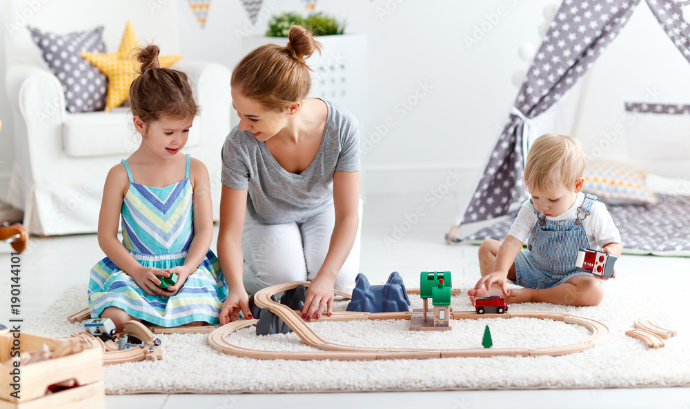 家庭母亲和孩子在游戏室玩玩具铁路