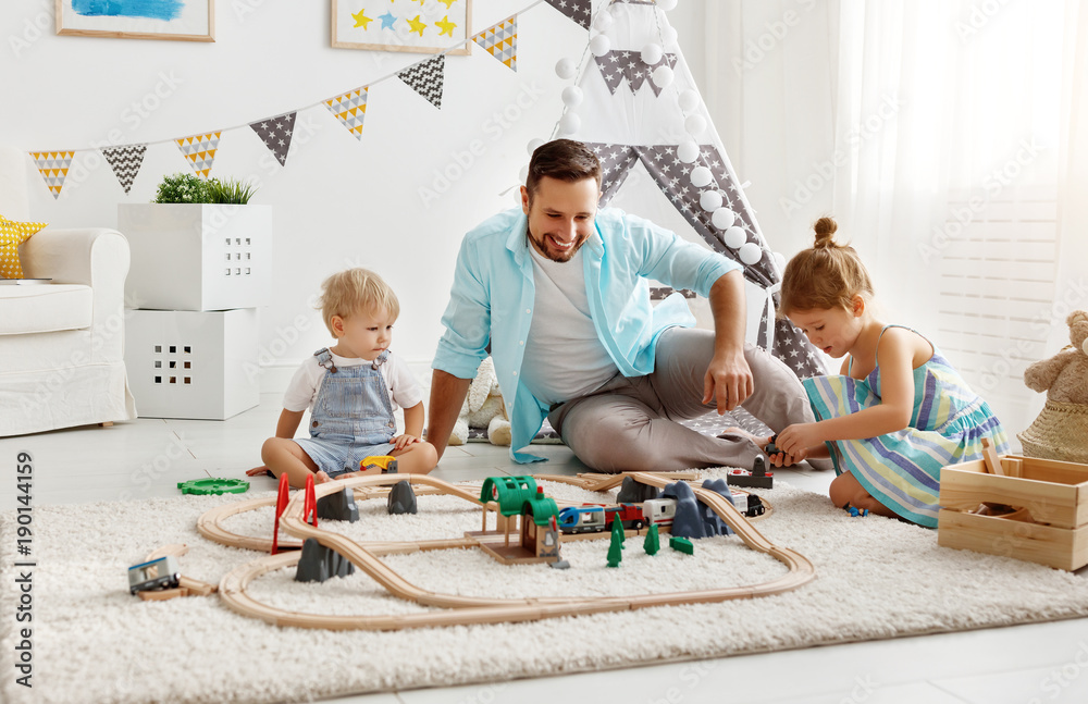 家庭父亲和孩子在游戏室玩玩具铁路