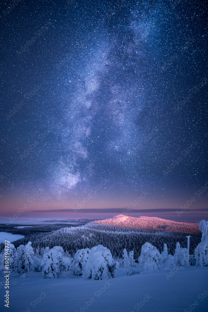 银河系和星星在冬季景观上方的天空中发光