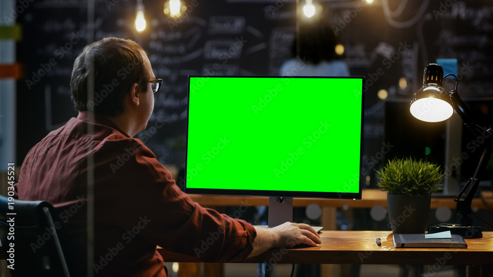 办公室员工在他的桌面上用模拟绿屏个人电脑工作。肩扛