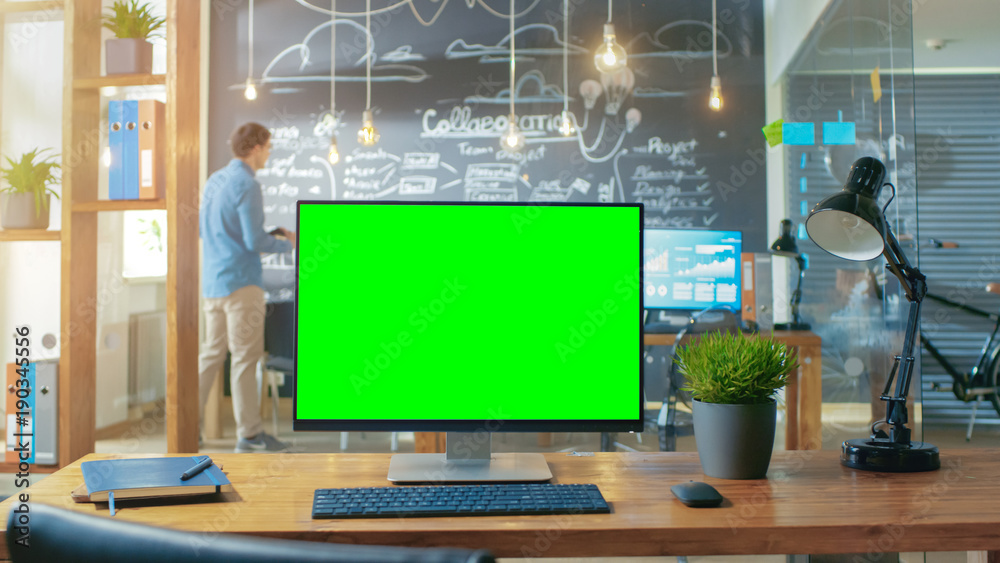 办公桌上放着带实体绿屏显示器的个人电脑，背景是男人